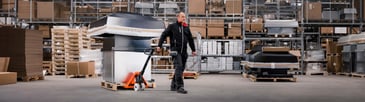 a warehouse worker operating a BT hand pallet truck safely