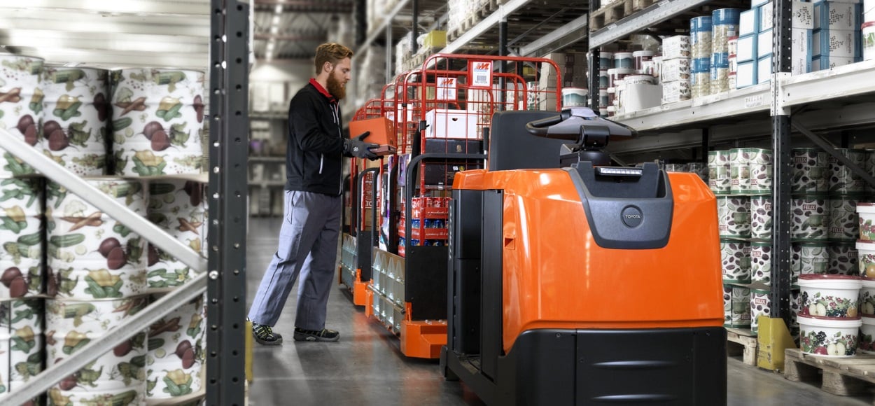 A toyota tow train being stacked by an employee whilst picking in a warehouse